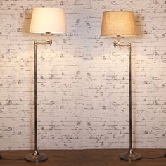 two lamps are sitting next to each other on a wooden table in front of a white brick wall