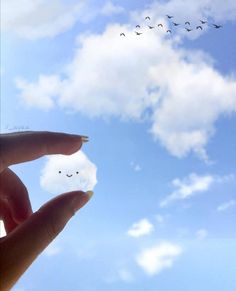 a person is holding their finger up to the sky with birds flying in the background