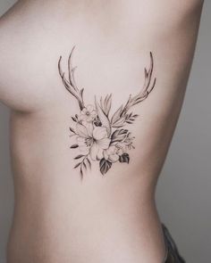 a woman's stomach with flowers and antlers on her side, while she is wearing