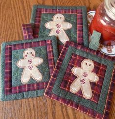 three coasters with embroidered gingerbread men on them sitting on a table next to a mason jar