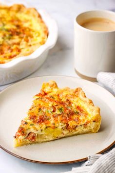 a slice of quiche on a plate next to a cup of coffee