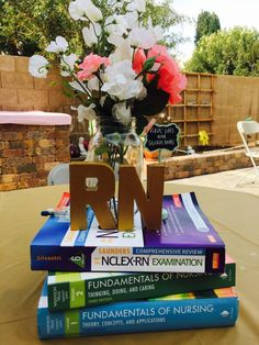 a stack of books sitting on top of a table next to a vase filled with flowers