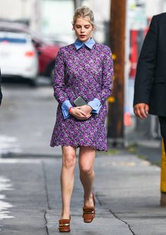 a woman in a purple dress is walking down the street