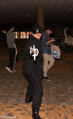 a young boy dressed in black and holding two skateboards while walking through an airport