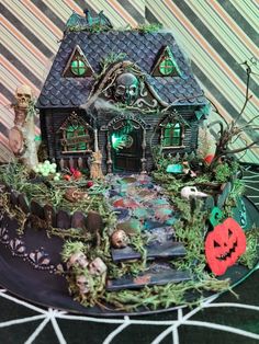 a halloween themed cake on a plate with decorations and lights in the shape of a house