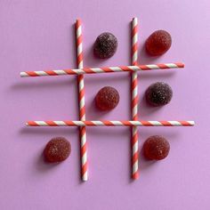 four strawberries and two candy sticks on a pink surface