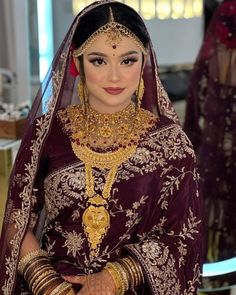 a woman in a maroon and gold bridal outfit