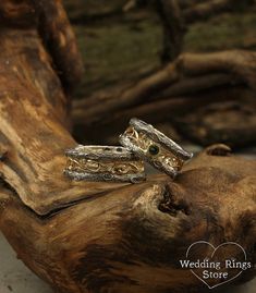 two wedding rings sitting on top of a piece of driftwood next to each other