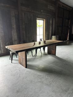 a long table in an old barn with chairs around it and a window on the wall