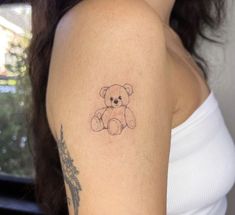 a woman's arm with a small tattoo of a teddy bear on the left shoulder