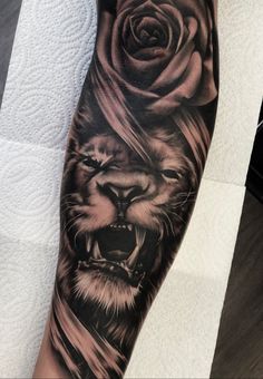 a man's arm with a lion and rose tattoo on it