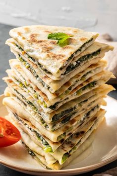 a stack of flatbreads on a plate next to a tomato