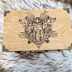 a wooden box with an intricate design on the front and sides, sitting on top of some fur