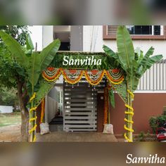 an entrance to a building decorated with flowers and garlands on the outside, surrounded by trees