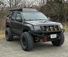 a black four door suv parked on top of a gravel road