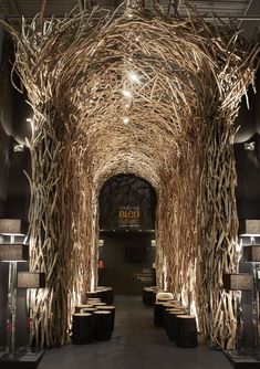 the entrance to an art gallery with wooden sticks and lamps hanging from it's ceiling