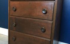 a brown wooden dresser sitting next to a blue wall