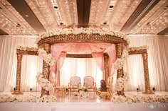 a wedding ceremony setup with white flowers and pink draping on the stage,