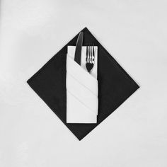 a napkin and fork on top of a black square with a white napkin underneath it