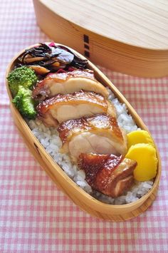 a bento box filled with rice, meat and veggies on a table