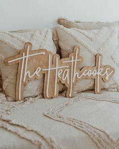 two wooden signs sitting on top of a bed next to pillows and throw pillows with the words the heathcocks