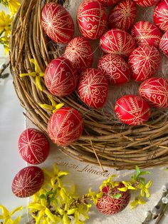 a basket filled with red eggs sitting on top of a table next to yellow flowers