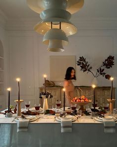 a woman standing in front of a table filled with food and candles on top of it