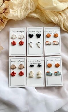 six pairs of earrings with bows and pumpkins on them sitting on a white sheet