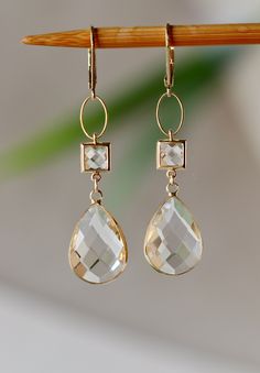 Beautiful, elegant Earrings with Clear Faceted Glass Square Connectors 7 x 7 mm Faceted Clear Glass Drops clear like drop of Water 17 x 11 mm. in Gold plated Bezel frame Gold plated Lever back Ear Clasp. The total length is 2.25 inches or 58 mm long.  Your order will be wrapped and shipped in jewelry gift box. * * * * * * * * * * * * * * * * * * * * * * * * * * * * * * * * * * * * * * * * * *  If you would like to order this item as a gift you can leave a personalized note for the receiver durin Cheap Clear Drop Earrings, Elegant Clear Earrings As Gift, Classic Faceted Wedding Earrings, Wedding Jewelry With Matching Clear Earrings, Classic Wedding Faceted Earrings, Elegant Drop Earrings With Faceted Details, Elegant Hypoallergenic Briolette Earrings, Briolette Yellow Gold Earrings For Weddings, Yellow Gold Briolette Earrings For Wedding