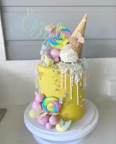 a yellow cake with ice cream and candies on top is decorated in pastel colors