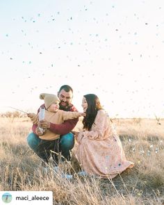 a man and woman holding a baby in a field with confetti falling from the sky