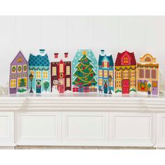 a group of colorful houses sitting on top of a white mantle next to a christmas tree