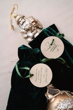 a green velvet bag with two tags on it next to a gold ornament