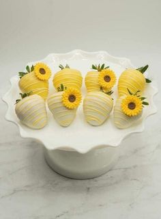 chocolate covered strawberries with yellow flowers in a white bowl on a marble countertop