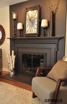 a living room with a fireplace, chair and clock on the wall in front of it