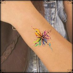 a woman's arm with a colorful ink splattered tattoo on it,