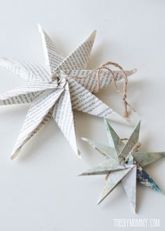 three origami stars made out of book pages on a white surface with twine