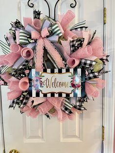 a welcome wreath with pink and black ribbons on the front door, decorated with an ornate welcome sign