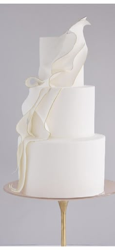 a three tiered white wedding cake sitting on top of a gold plated stand