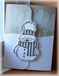 a handmade christmas card with a snowman on the front and trees in the back