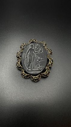 This vintage black cameo brooch pin features a standing lady with birds design, framed in gold with black stones. The oval shape and black color of the brooch make it a unique addition to any collection. Measures at 2.25" x 2.75". Shop more items: https://www.etsy.com/shop/FayeVonTreasuresLLC (250) Black Cameo, Angel Brooch, Birds Design, Black Stones, Gold Pin, Blue Pin, Heart Brooch, Cameo Brooch, Silver Pin