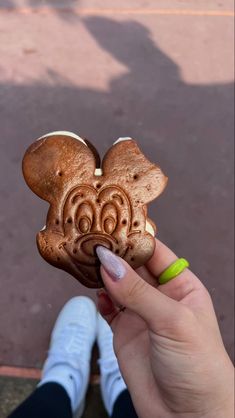 a person holding up a carved mickey mouse cookie in front of the camera with their hand