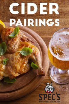 a wooden plate topped with chicken wings next to a glass of beer