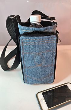 a cell phone is sitting next to a blue denim bag with a water bottle in it