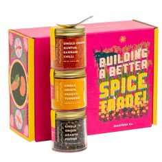 four spice boxes are stacked on top of each other in front of a pink box