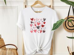 "Wrap your love in a vibrant embrace with our Heartful Harmony T-shirt! 🌈 Overflowing with joy, with the key features a kaleidoscope of brilliantly coloured hearts. Each colour signifies a unique moment, a cherished memory. Let your heart speak louder than words. Gift the magic of love. Wear the warmth, share the joy. Because every heartbeat deserves a celebration!  #HeartfulHarmony #LoveInEveryHue" ✨Sizing✨ Please note that the T-Shirt and its sizing is unisex. Please review the sizes in the l Valentine's Day Graphic Tee With Heart Print, Valentine's Day Heart Print Graphic Tee, Pink T-shirt With Funny Print For Valentine's Day, Valentine's Day Pink T-shirt With Funny Print, Heart-shaped T-shirt For Valentine's Day, White T-shirt For Valentine's Day Gift, Valentine's Day Heart Print Tops, Mother's Day Short Sleeve T-shirt With Heart Print, Heart Shaped Graphic T-shirt For Valentine's Day