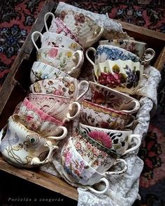 a wooden box filled with lots of different kinds of cups and saucers on top of a table