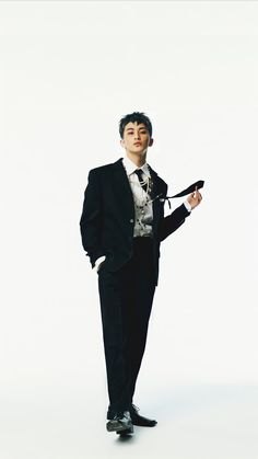 a man in a tuxedo is posing for a photo on a white background