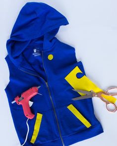 a pair of scissors and a blue jacket with yellow letters on the hood are laying next to each other