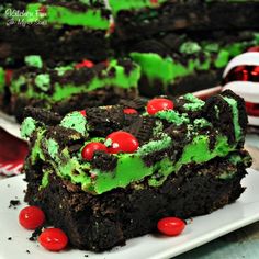 a piece of cake with green frosting and cherries on it sitting on a plate